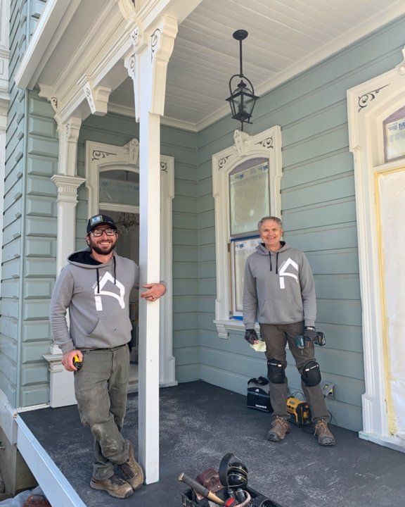 Two men are standing on the porch of a house.