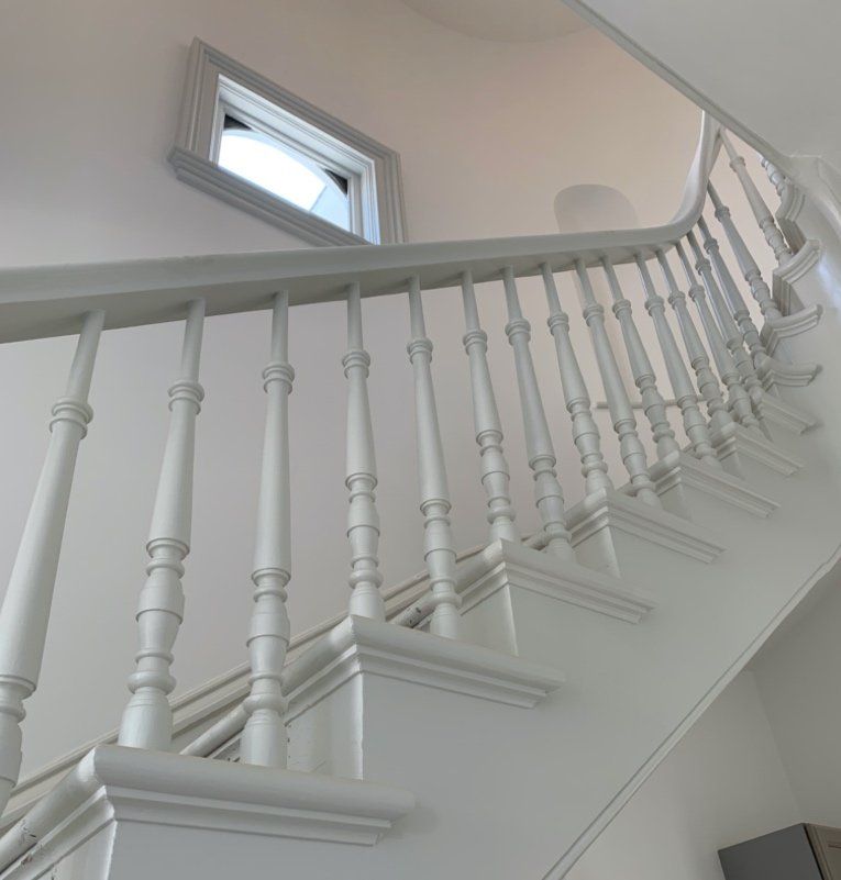 A white staircase with a railing and a window