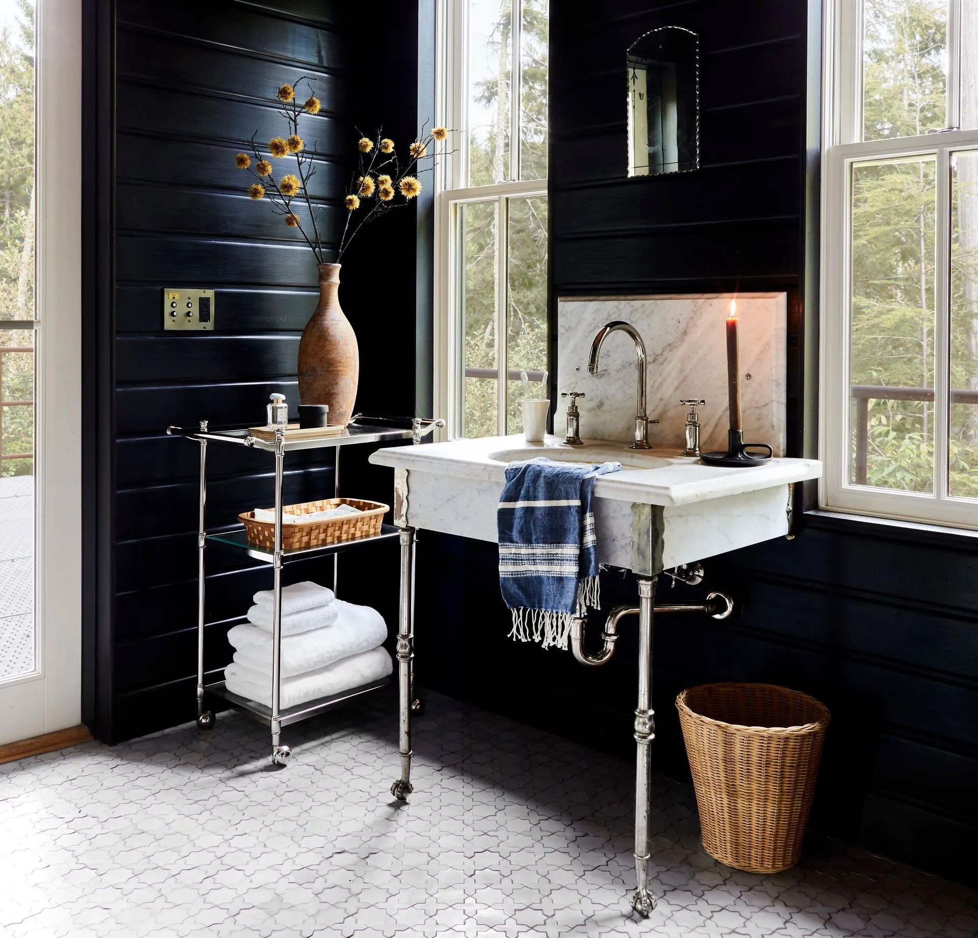 Tongue and groove walls painted black, handcrafted Zellige floor tiles, and a marble and nickel console sink create space that is rustic and moody, yet sophisticated. 