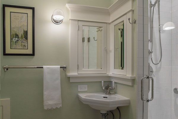 Small bathroom with a sink, mirror cabinet, towel rack, and glass shower enclosure.
