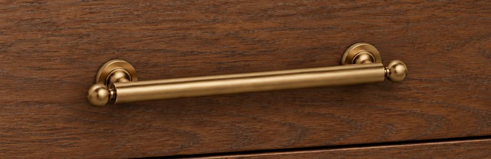 Cabinet hardware antique brass bin pull on dark stained wood drawer.