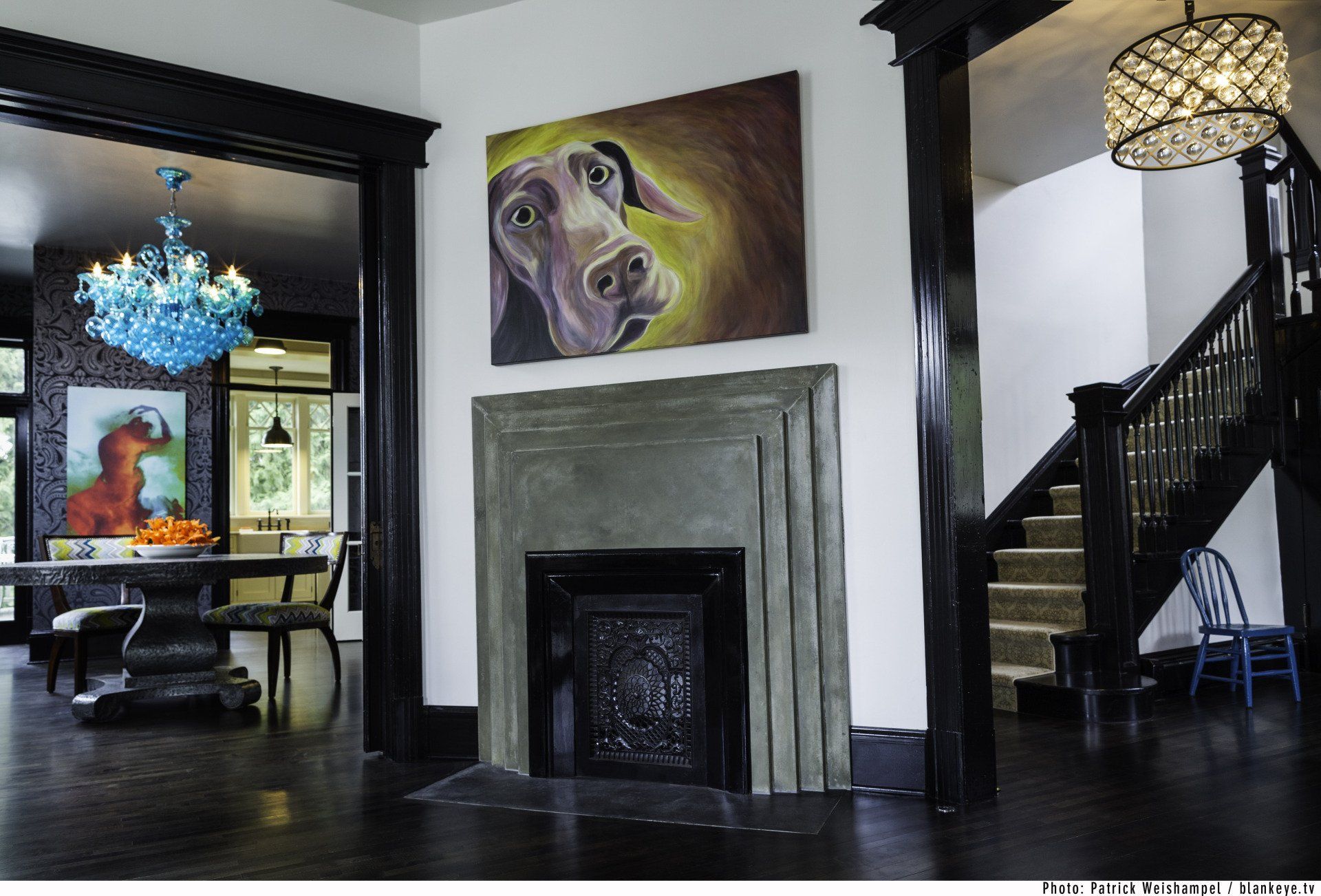 Looking at the dining room through a cased opening with the living room; there is a dog portrait above the fireplace.