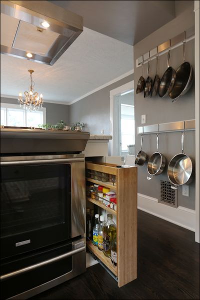 Modern kitchen with hanging pots and a pull-out spice pantry beside a stove