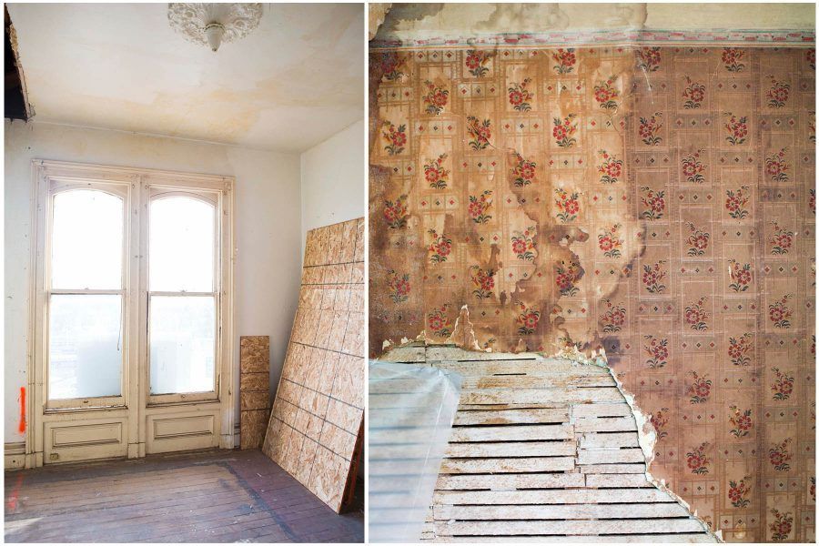 Peeling wallpaper and damaged plaster in a small room with a tall window and leaning boards.