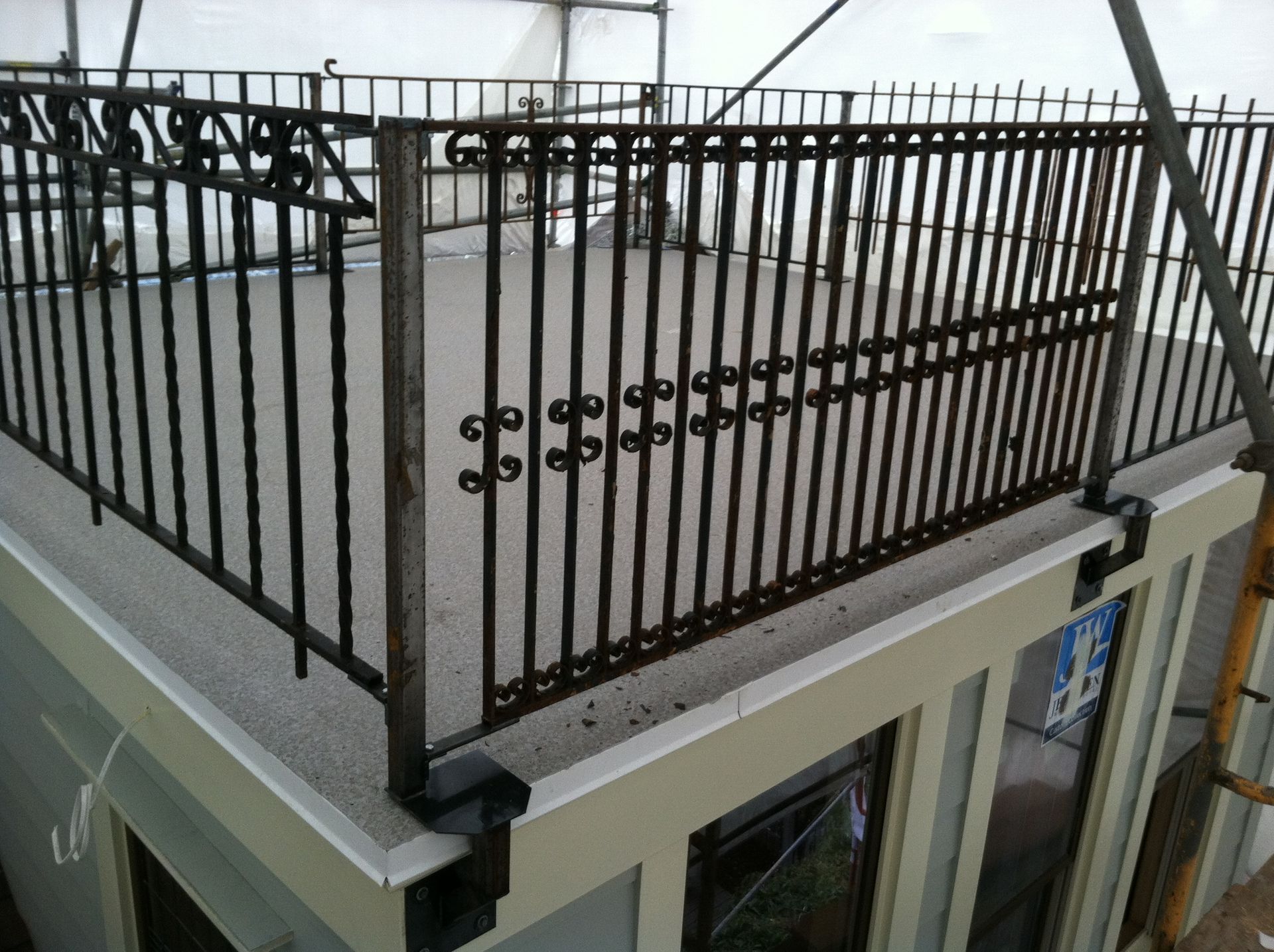 Black metal rooftop railing around a building terrace with a row of dark objects along the top rail