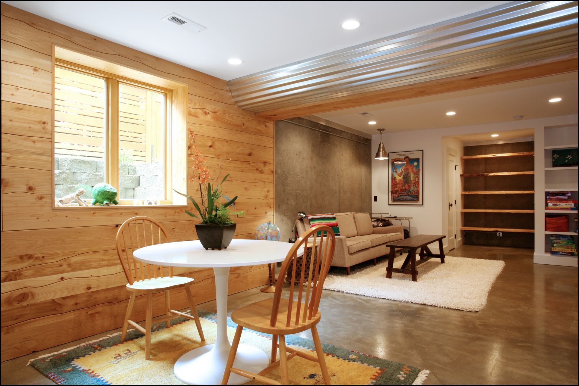 Cozy wood-paneled living room with a dining table, sofa, rug, and built-in shelves under warm lighting