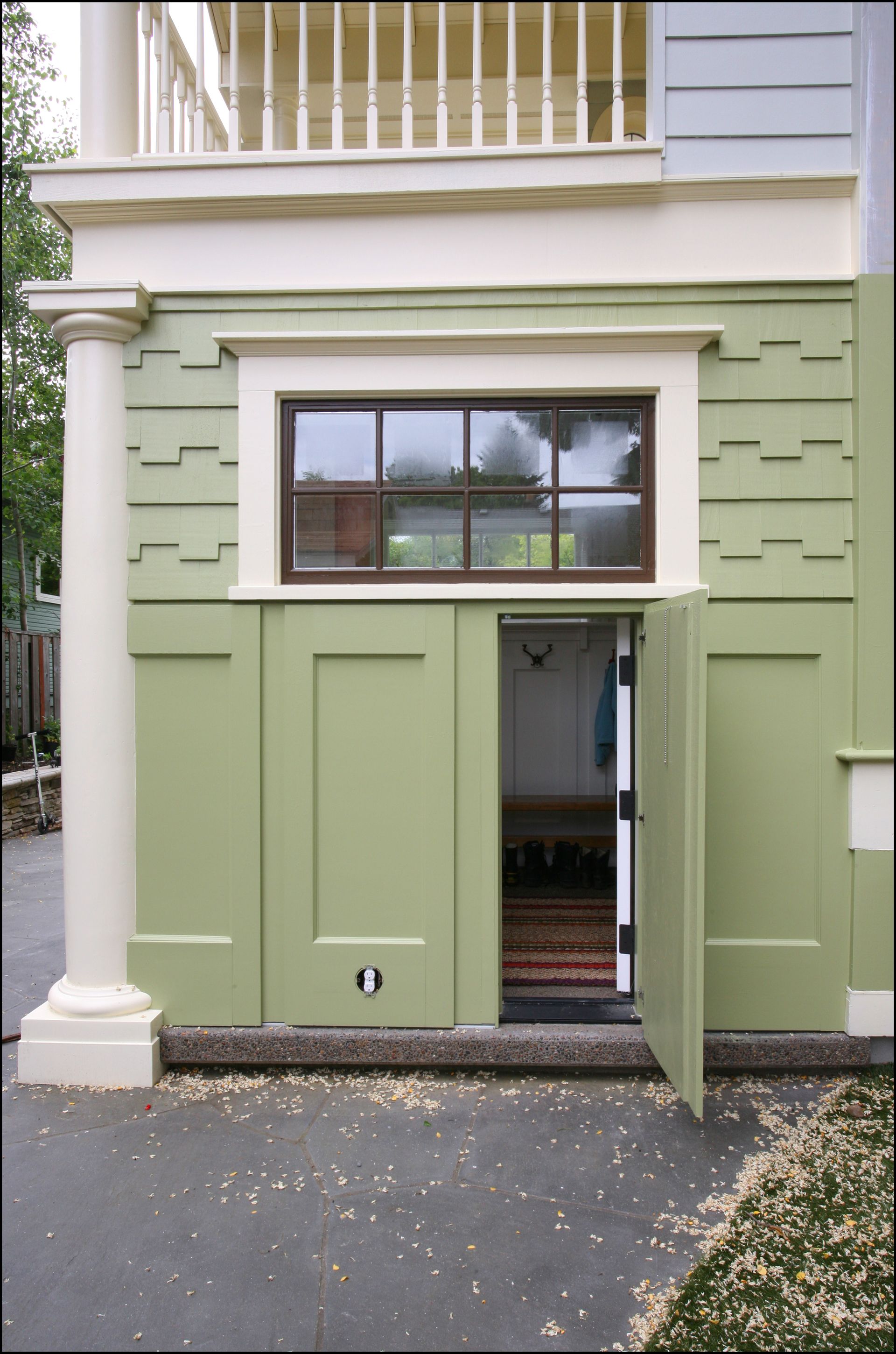 Open green doorway in a pale green building facade with a window above.