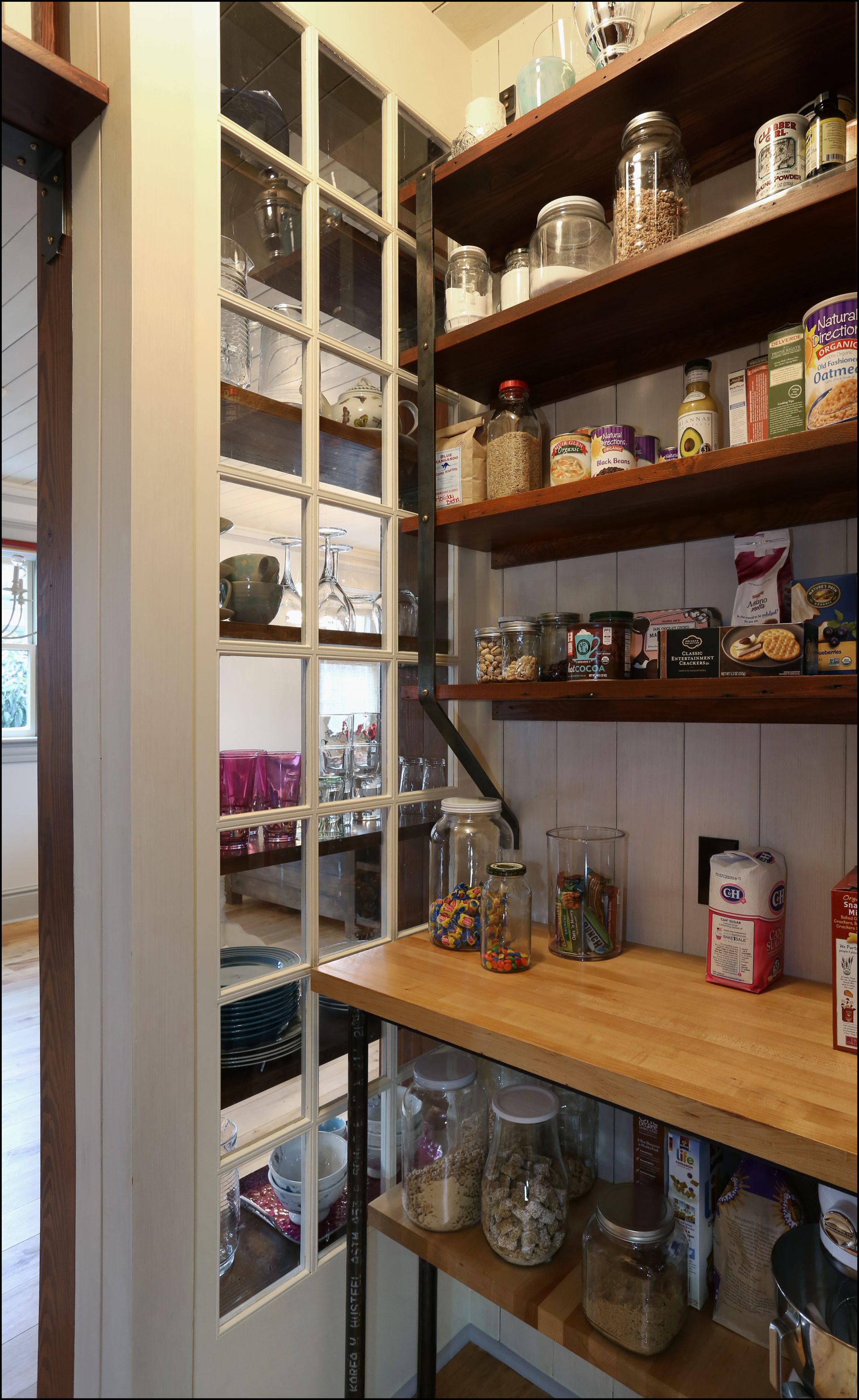 Pantry shelves with jars, canned goods, and packaged food in a narrow storage room