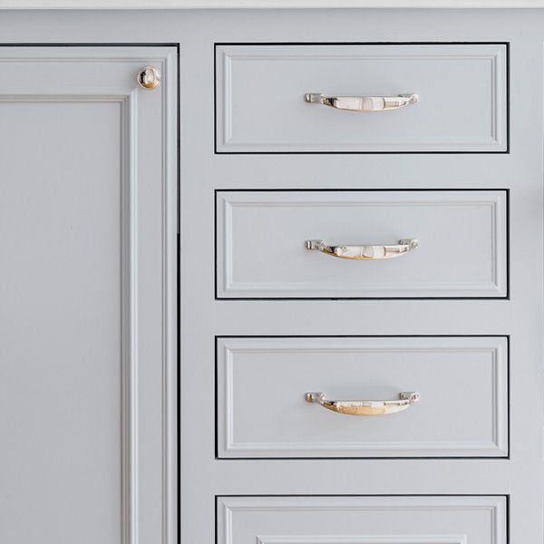 Unlacquered brass door and cabinet hardware on white kitchen cabinets. 