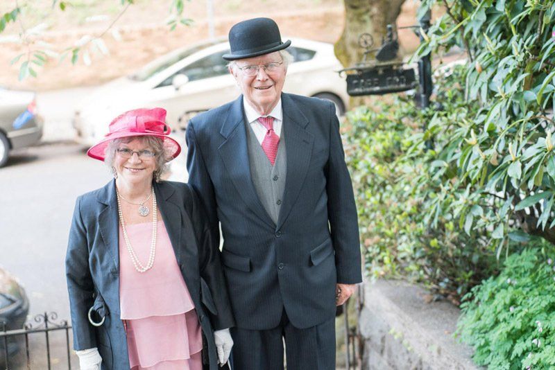 A man and a woman in suits and hats are standing next to each other.