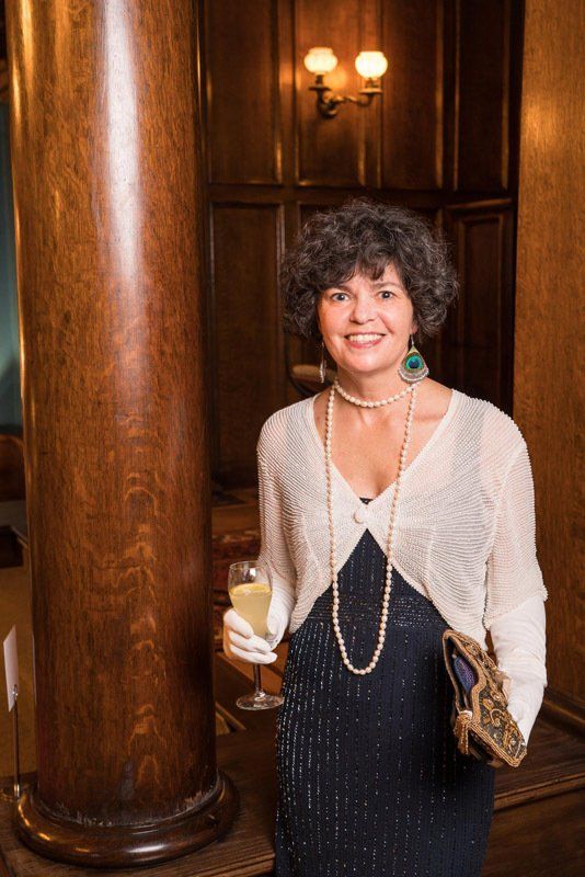 A woman in a black dress is holding a glass of wine.