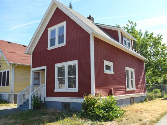 A red house with white trim is next to a yellow house