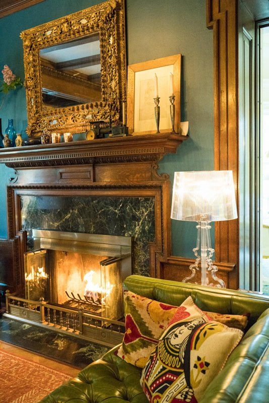 A living room with a fireplace , couch , lamp and mirror.