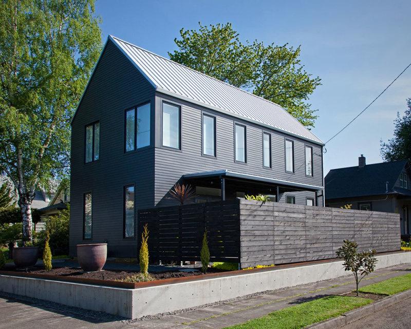 A black house with a white roof and a wooden fence