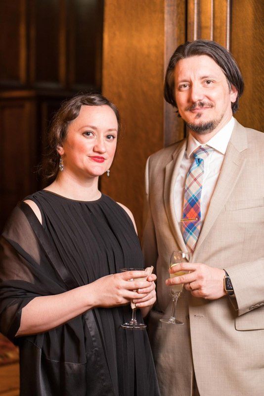 A man and a woman are standing next to each other holding wine glasses.