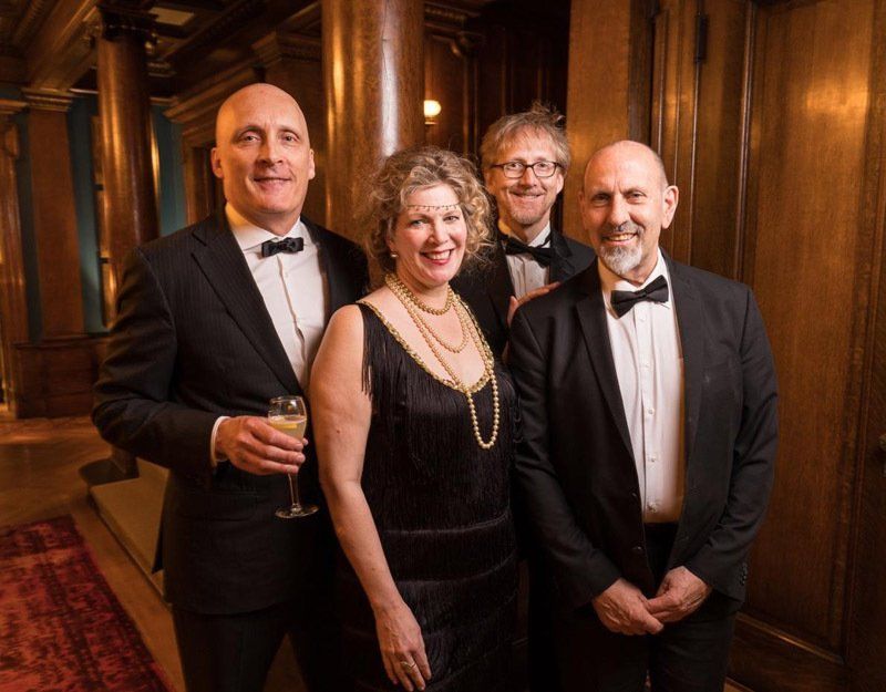 A group of people in tuxedos and bow ties are posing for a picture.