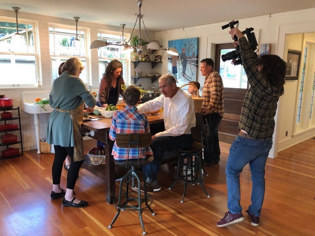 A man is taking a picture of a group of people in a kitchen.