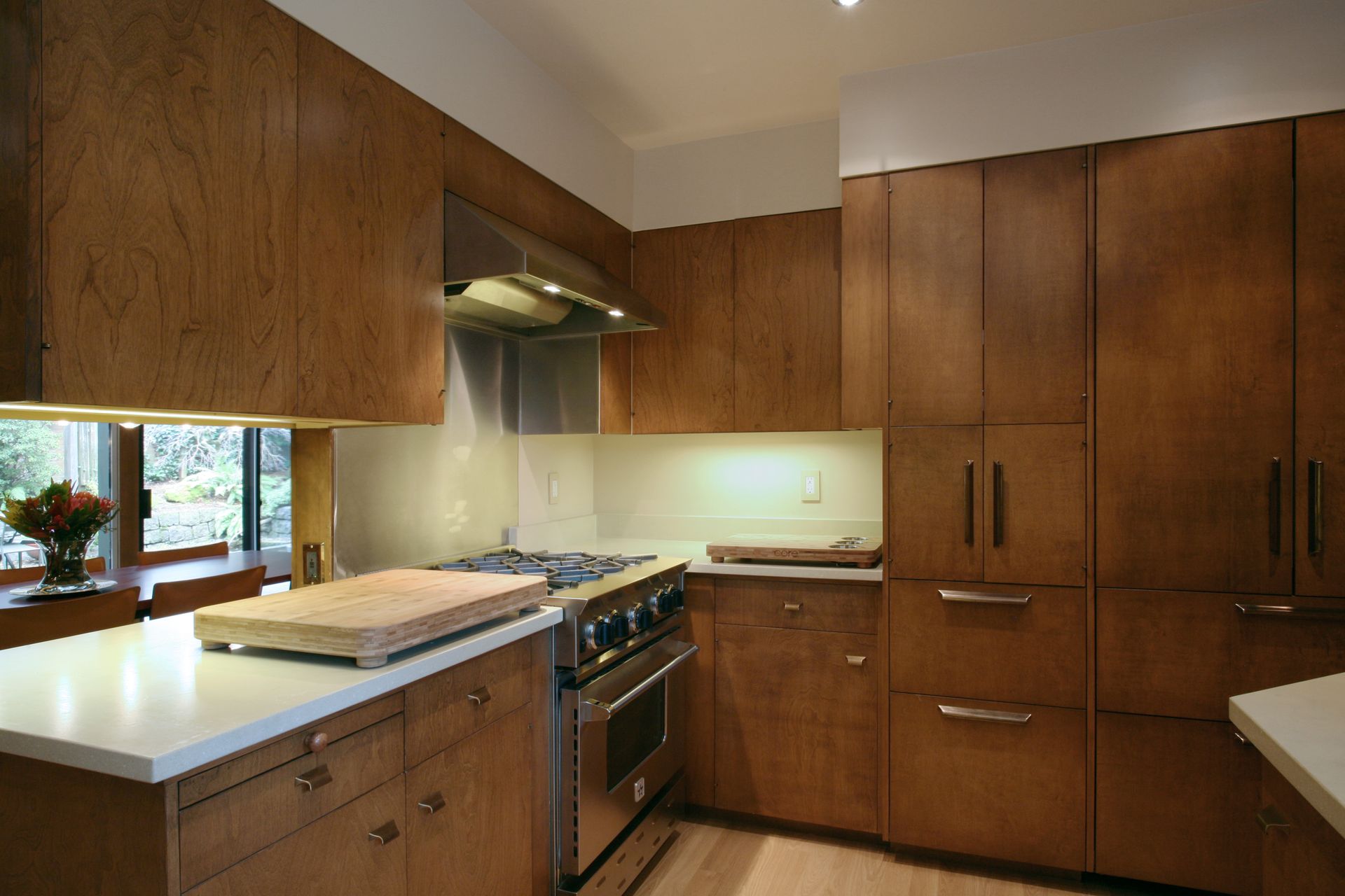 Modern wood kitchen with stainless stove, light countertops, and large cabinets