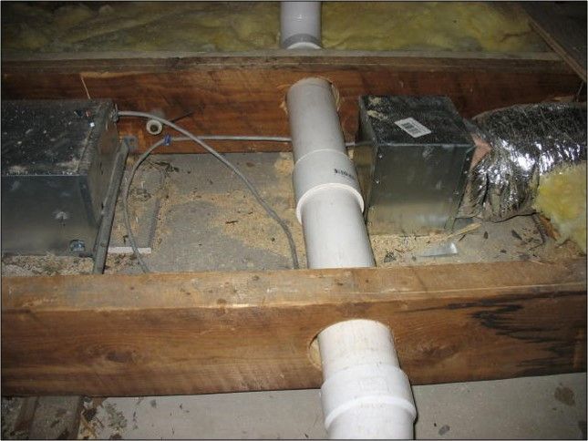 Attic HVAC ductwork and white PVC pipe between wooden joists, with metal vents and insulation