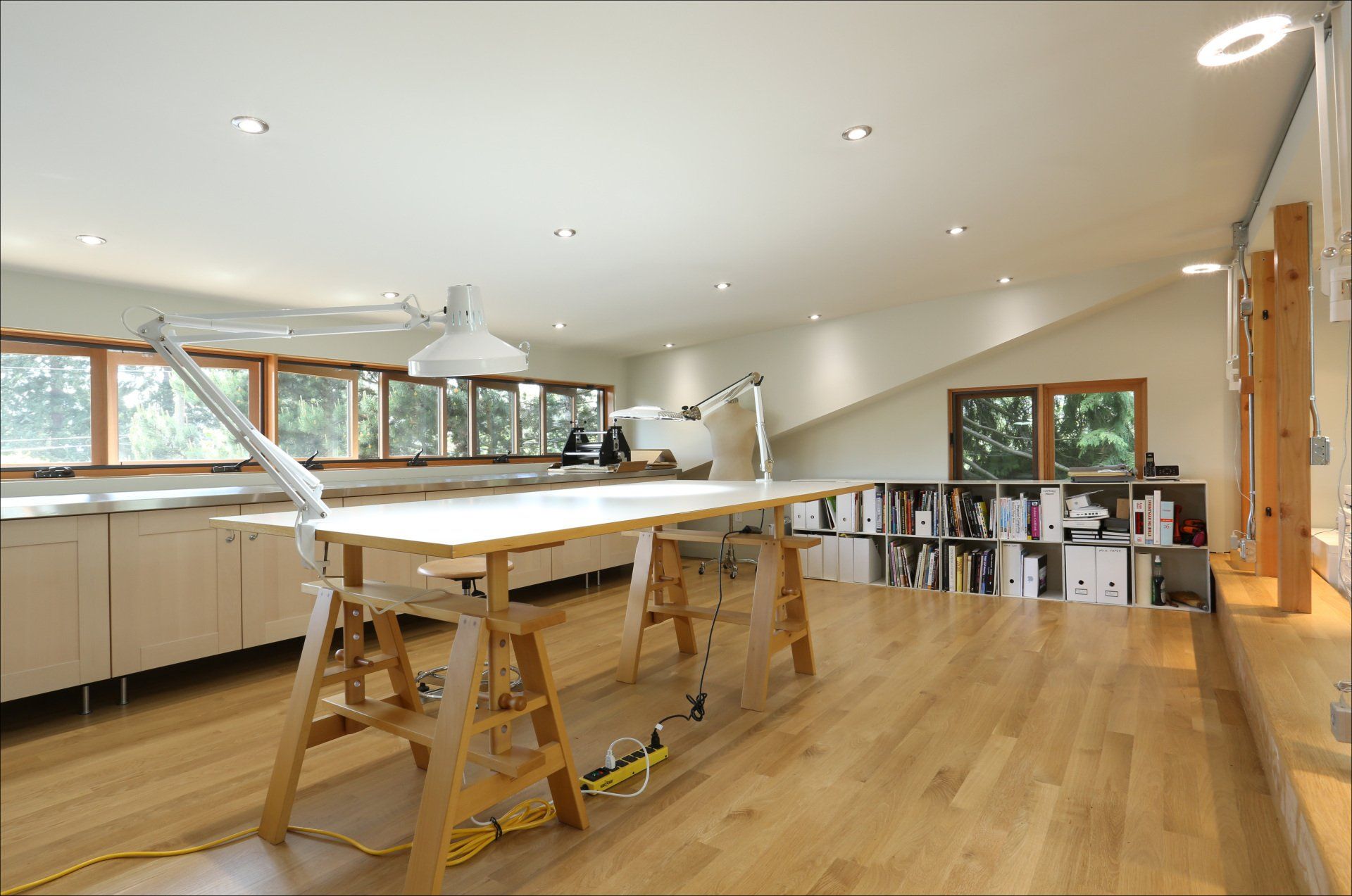 Looking from the back to the front of the studio, past the quilting table to the bank of windows.