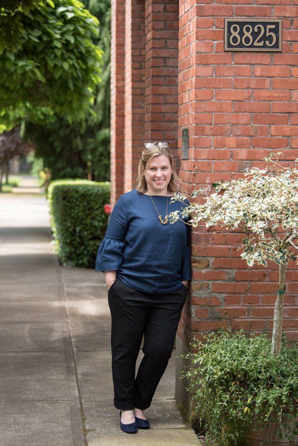 A woman is standing in front of a brick building.