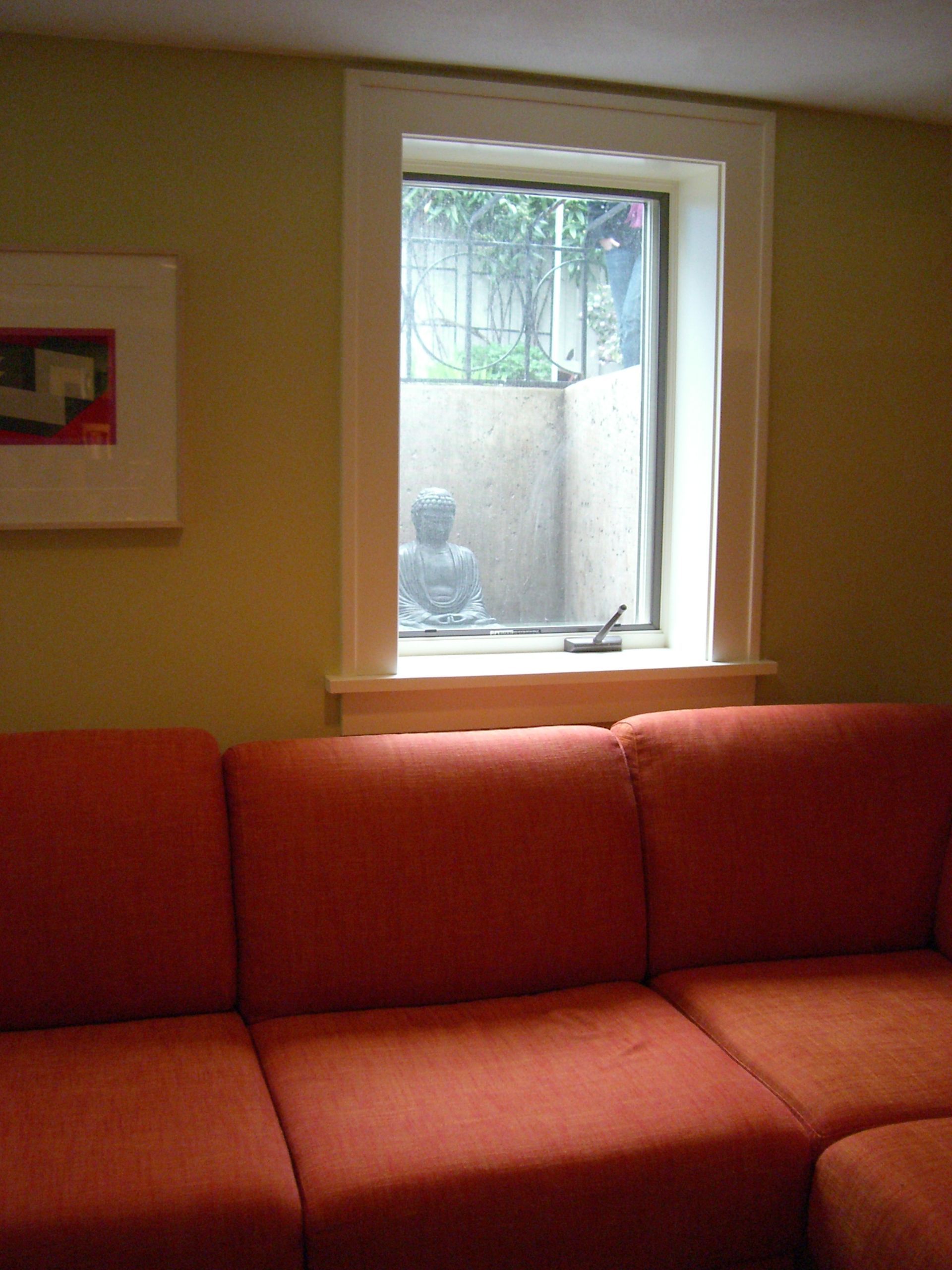 Orange sofa beneath a small window in a softly lit living room