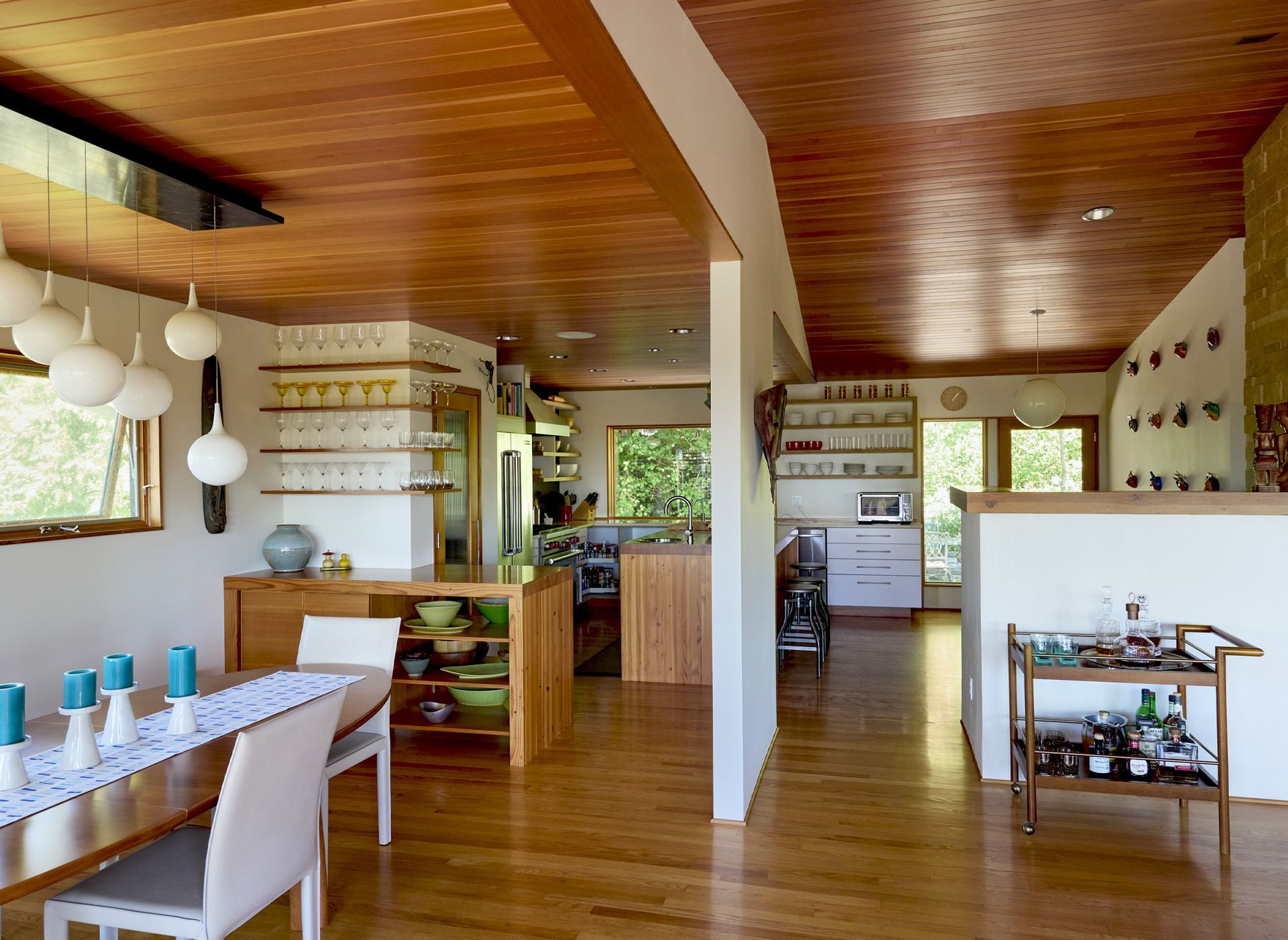 The living room, dining room and kitchen are open to one another with architectural elements that define the zones - the bar’s peninsula between the dining area and fridge and a half wall separating kitchen from living room.