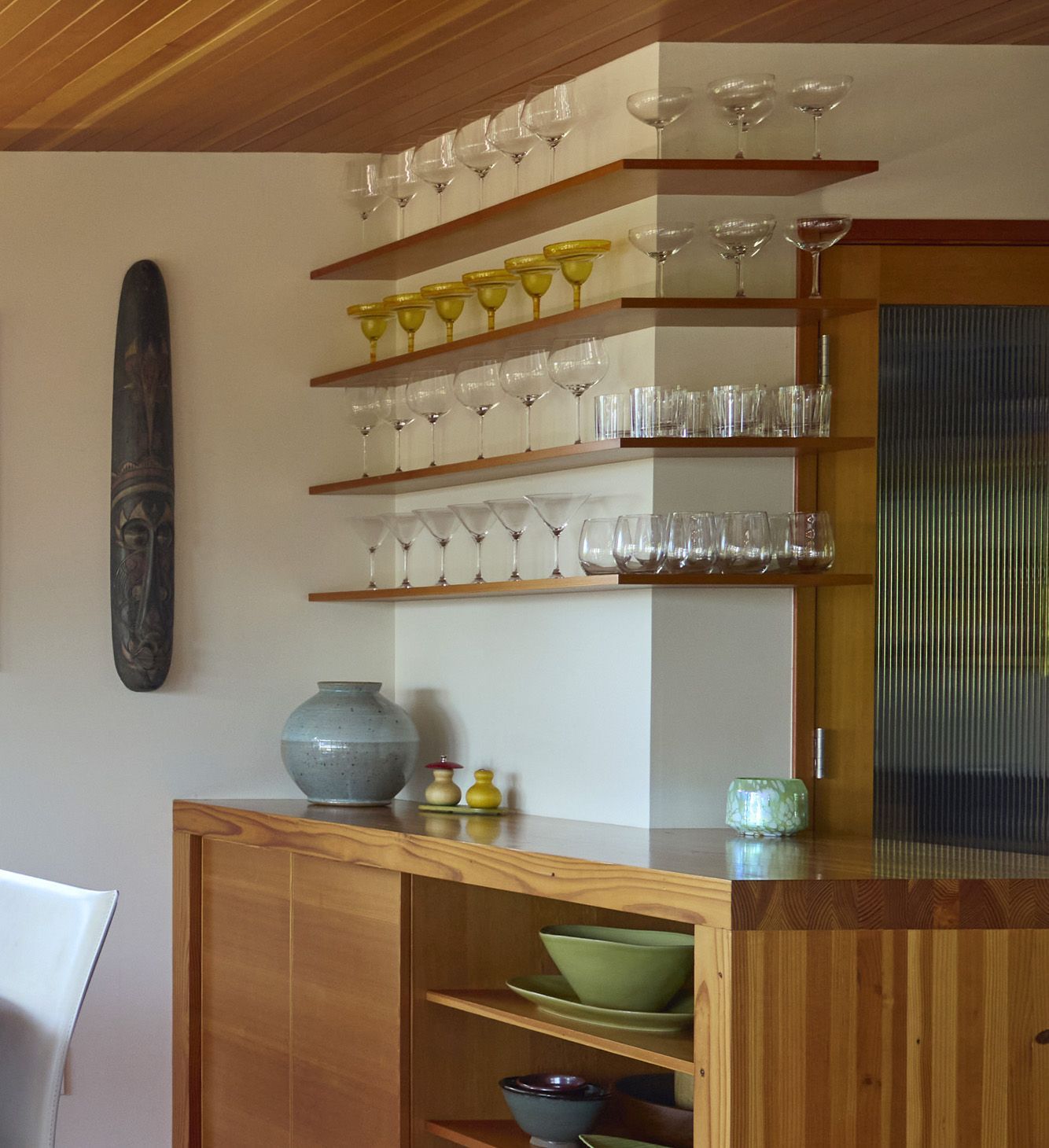 Facing the dining room, the bar’s custom wood shelves and buffet cabinet wrap around the outer corner of the kitchen pantry.