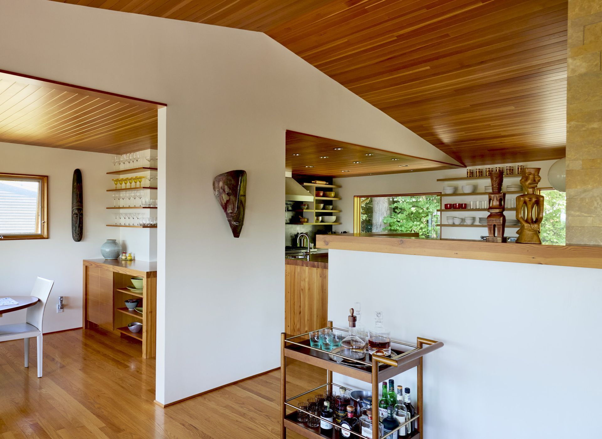 The living room, dining room and kitchen are open to one another with architectural elements that define the zones - the bar’s peninsula between the dining area and fridge and a half wall separating kitchen from living room.