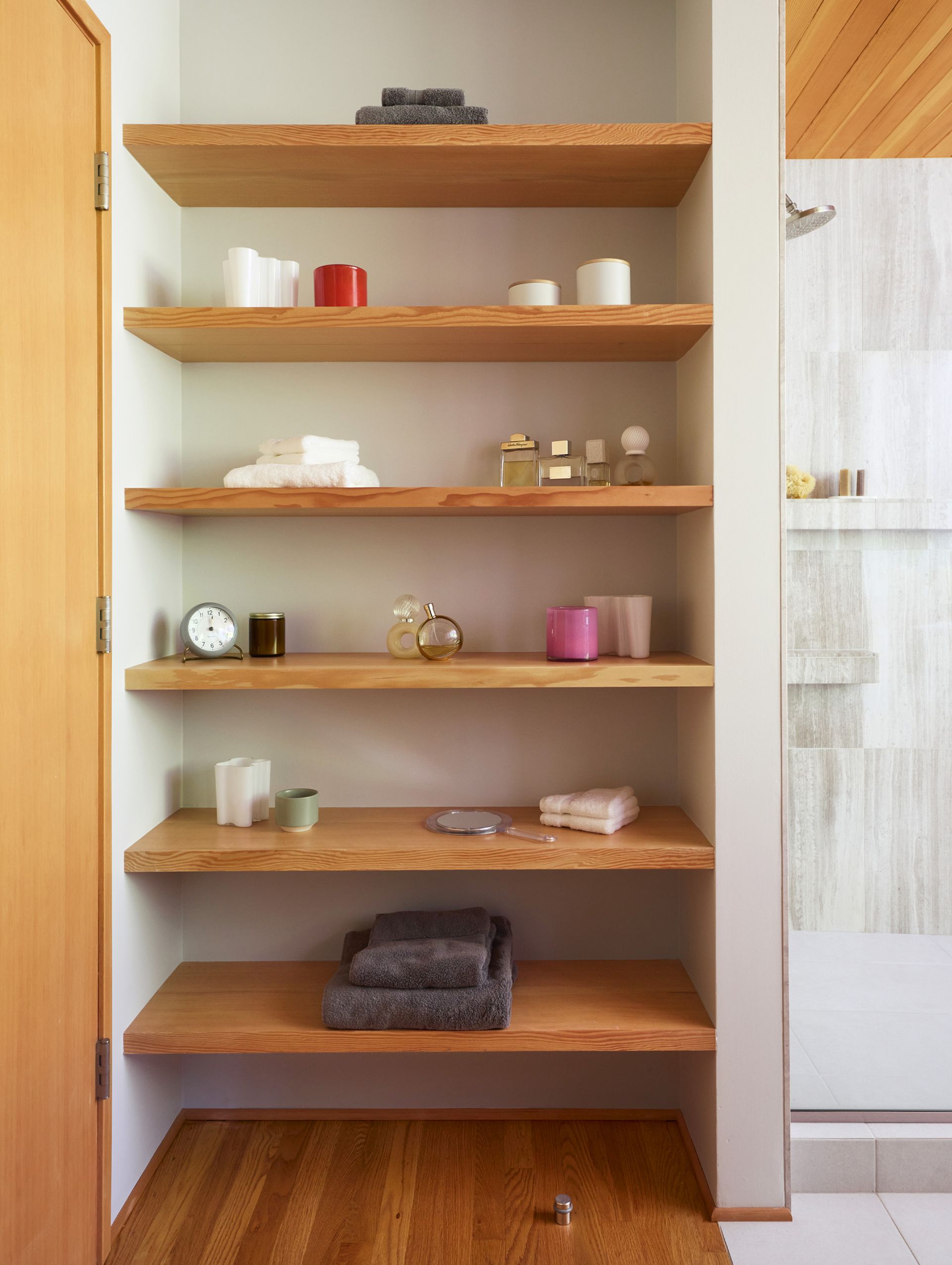 Alongside the shower is a full height niche with open fir shelving. Throughout the home, golden hues of fir millwork and oak flooring are balanced by simple white walls and natural stone tones.