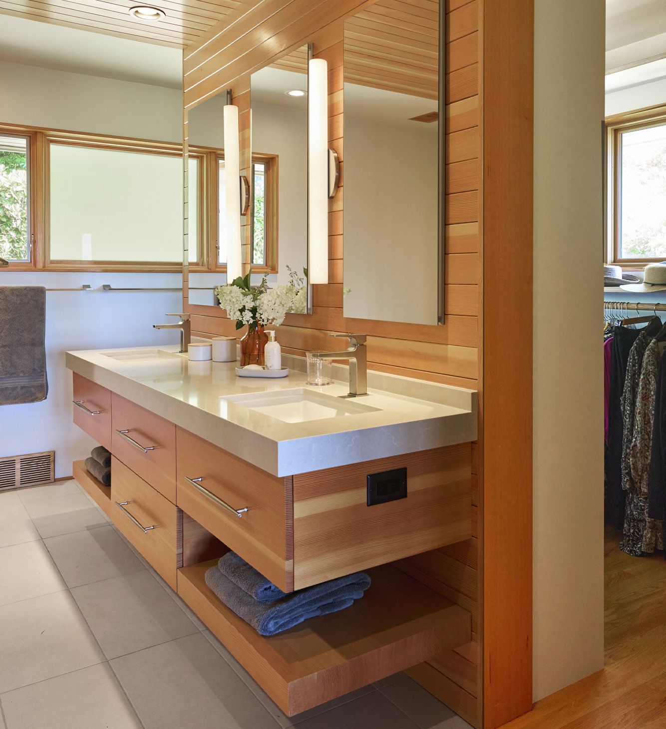 Entering from the main bedroom, you see the floating vanity on the right, with the walk-through main closet behind it. Natural light from South and East -facing windows brings a warm glow to the space.