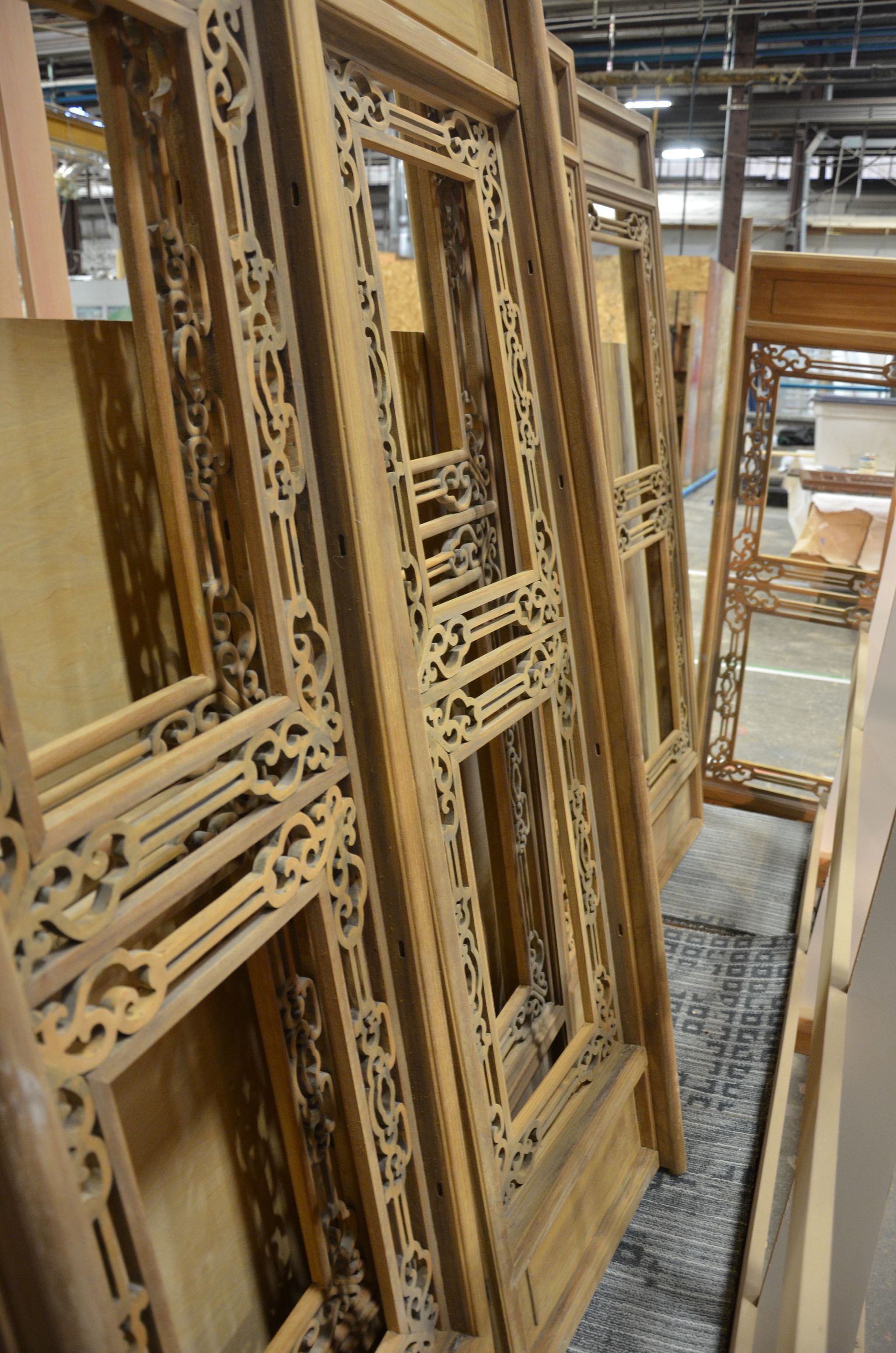 Stacked wooden carved window frames in a workshop or storage area.