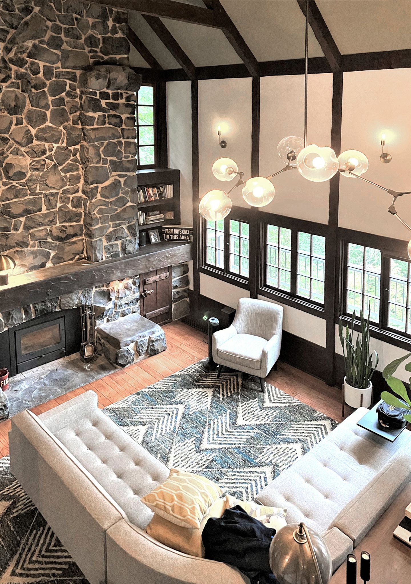 Looking down at the original living room with its full height fireplace, soaring ceiling and bank of original casement windows in this 1932 Tudor.