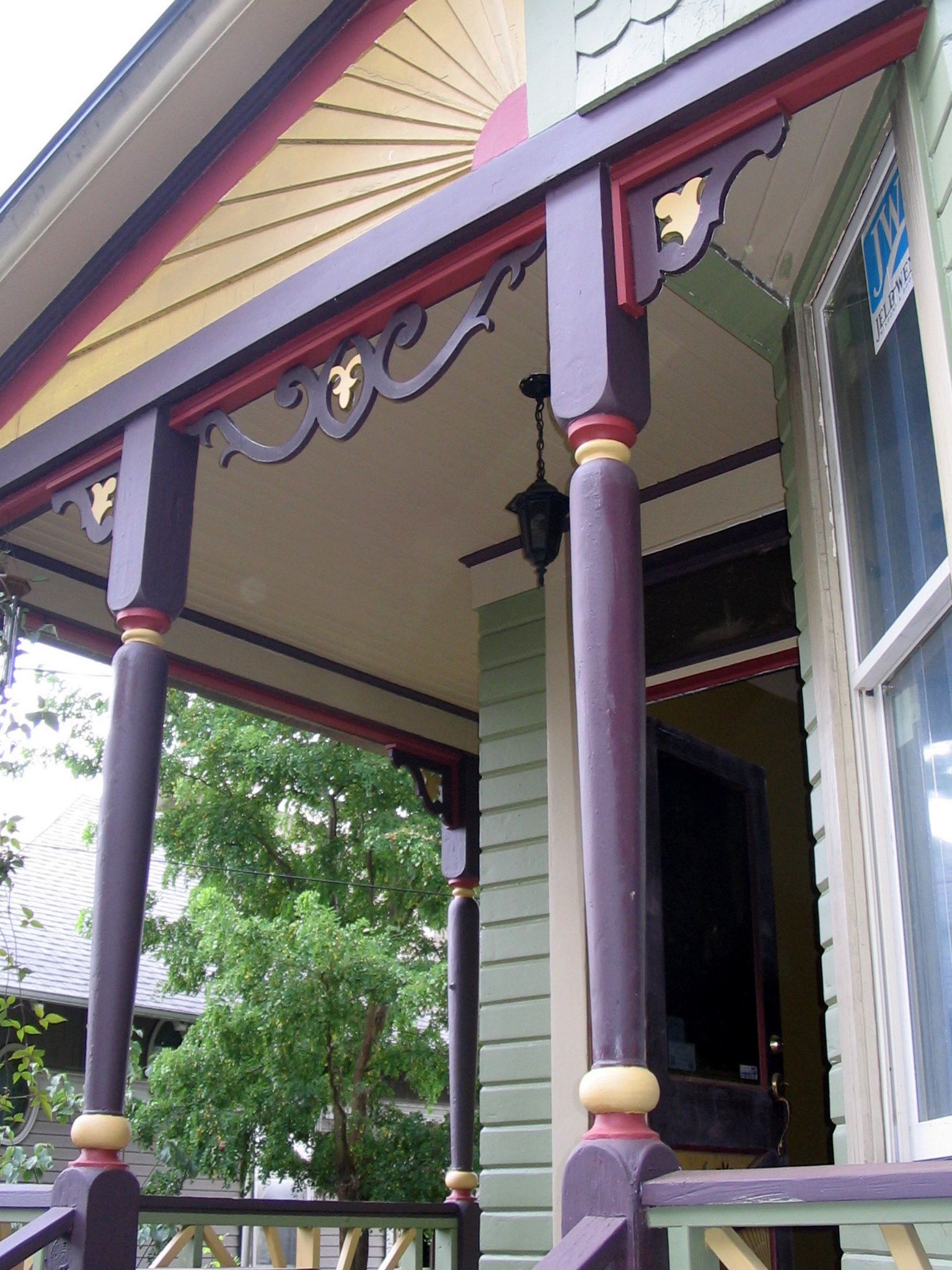 Victorian-style porch with purple columns, gold trim, and decorative woodwork, viewed from below