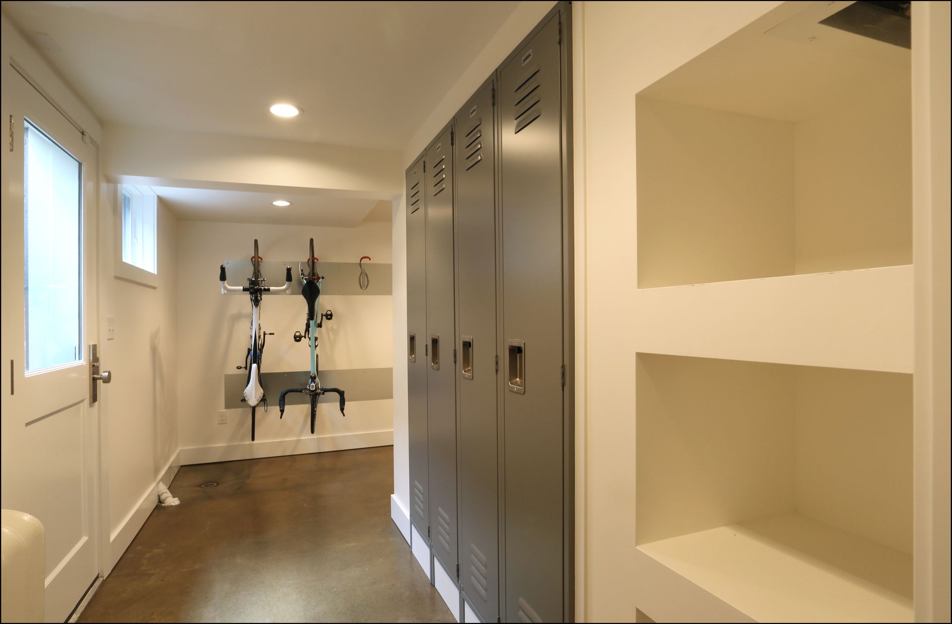 Bright hallway with built-in cabinets, shelves, and a small exercise bike at the far end.