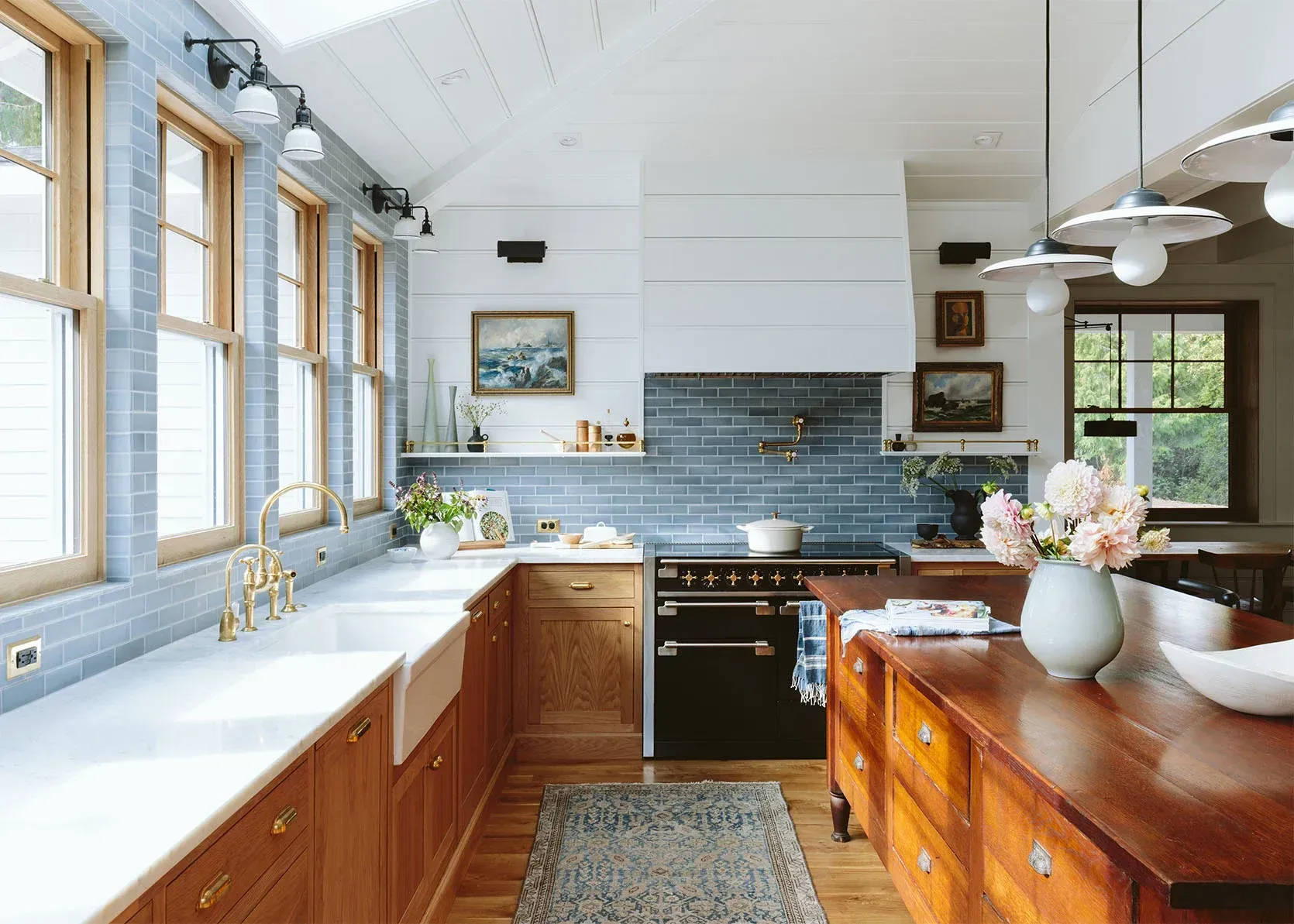 A kitchen with wooden cabinets , a black stove , a sink , and lots of windows.
