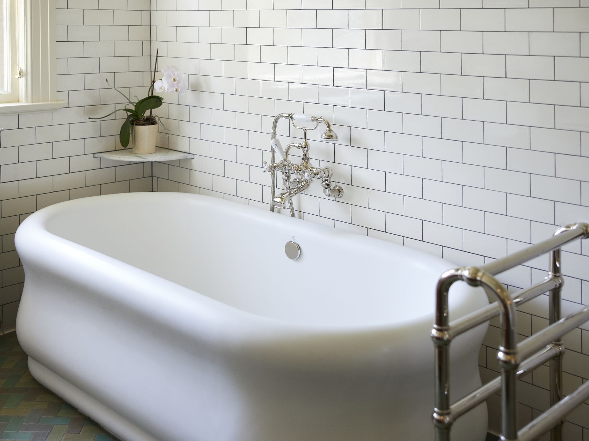 The freestanding tub with curvilinear lines has a towel warmer and wall mounted tub filler. 