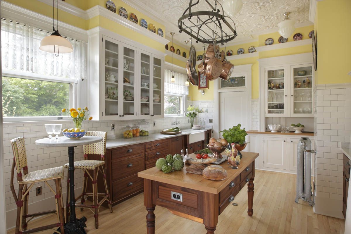 Bright kitchen with white cabinets, yellow walls, wooden island, and decorative pendant light