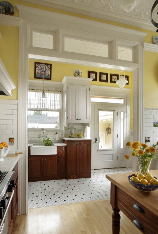 Bright white kitchen with yellow walls, wood cabinets, and a sunlit window above the sink.