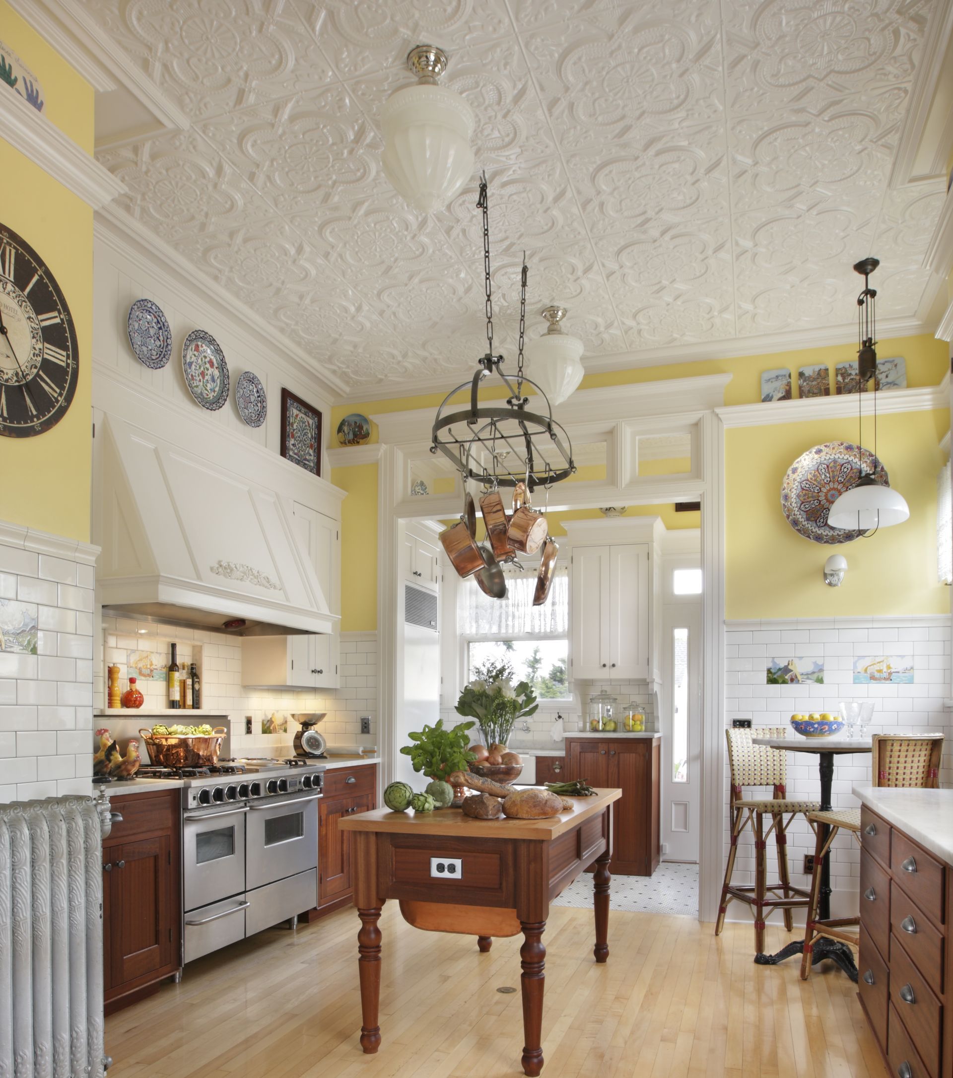Bright, traditional kitchen with cream cabinets, yellow walls, a central island, and hanging lights.