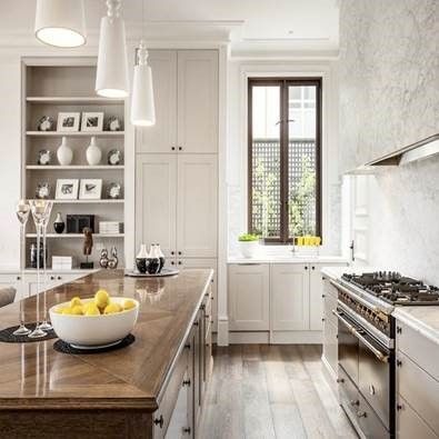 Bright modern kitchen with white cabinets, wood island, gas range, and bowl of lemons by a window