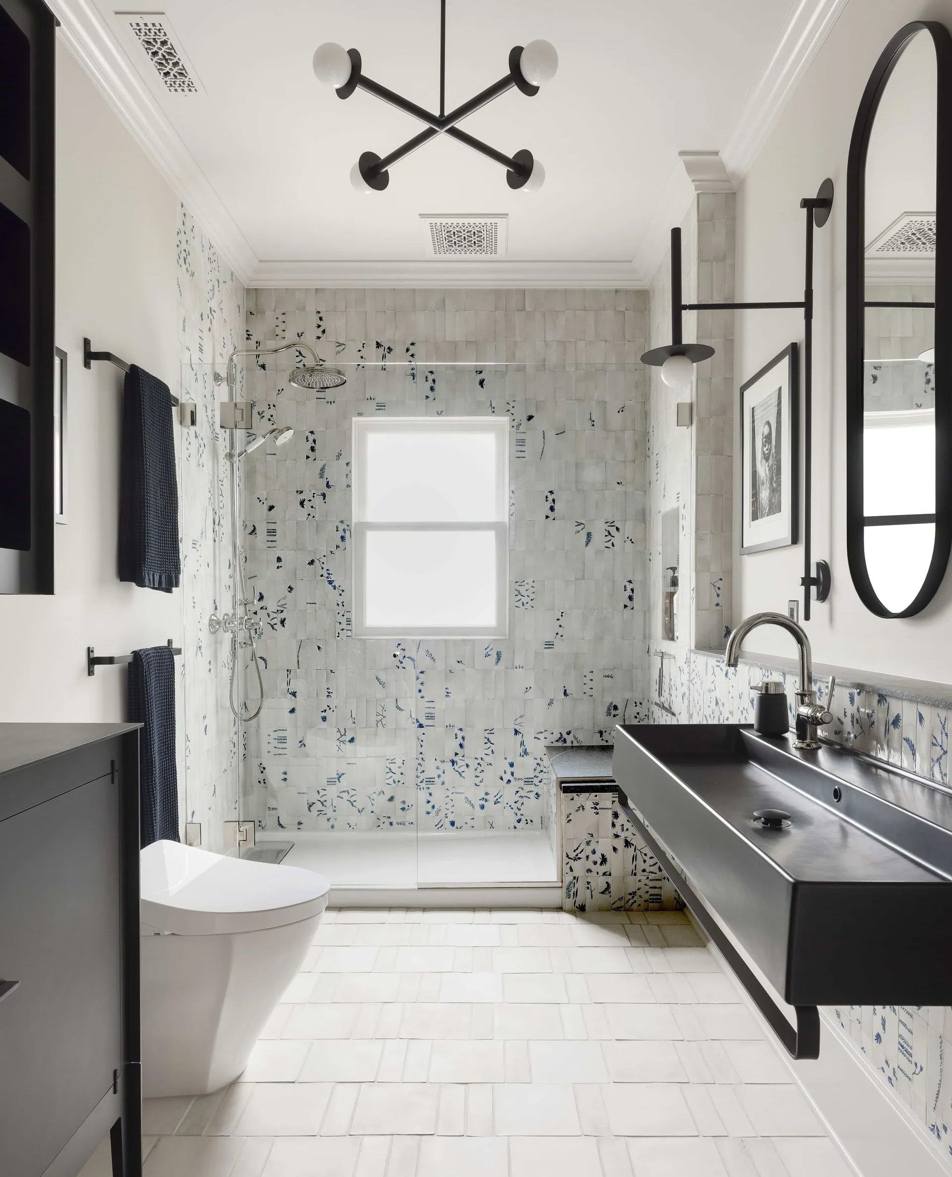 The after view of the bathroom shown in plan above features a luxurious walk-in shower with botanical-themed tiles and other modern touches. 