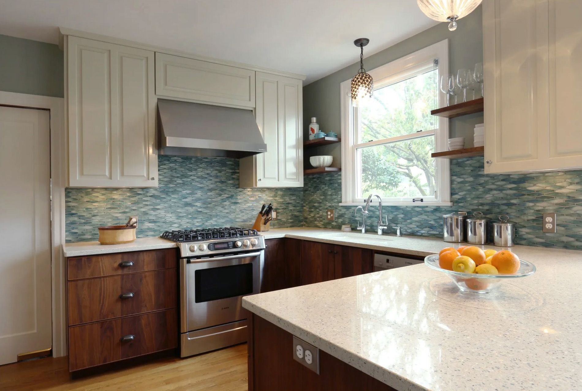 A bright, cheery kitchen with walnut lower cabinets and glass backsplash tile in pale ocean hues