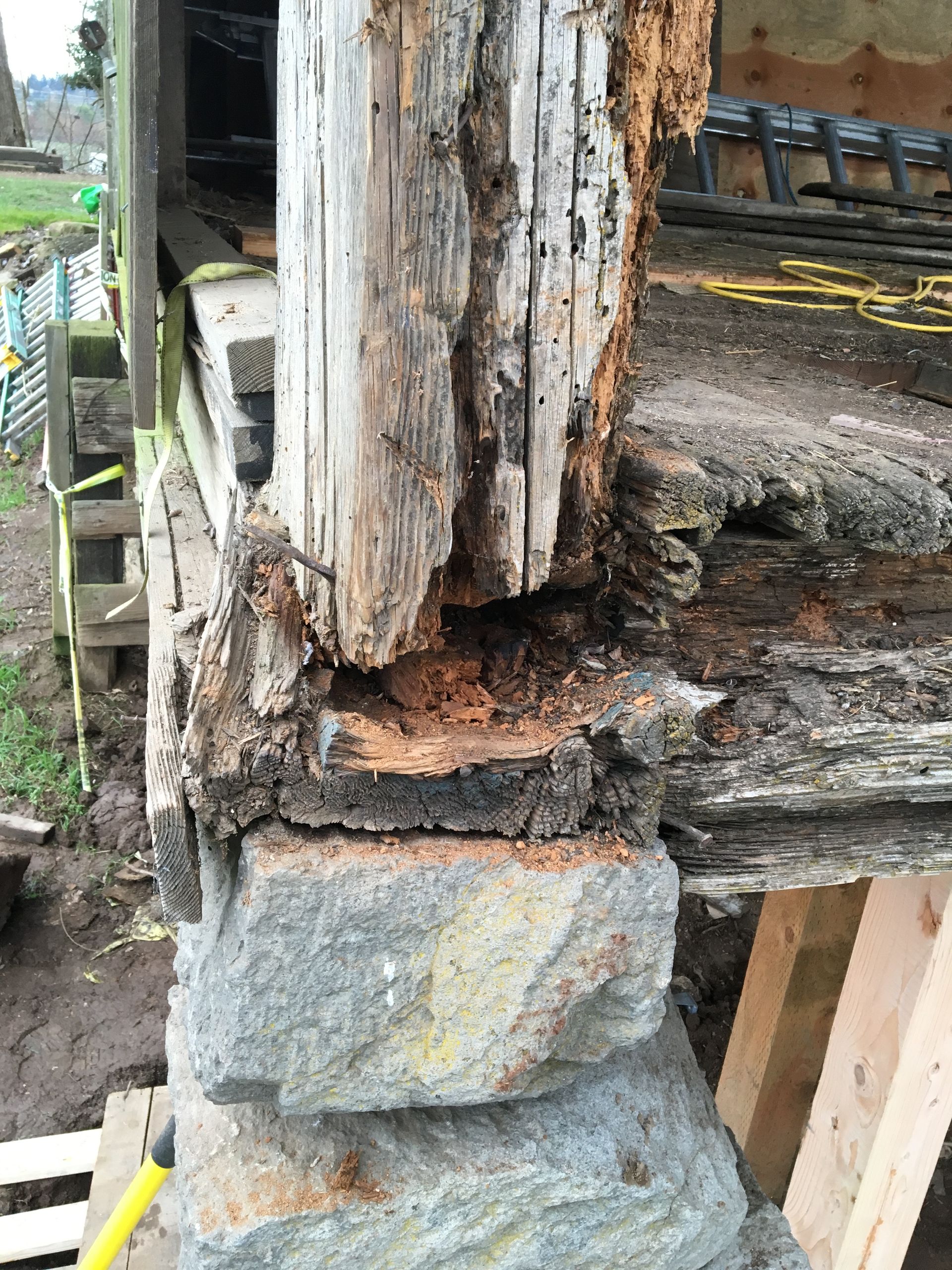 Rotted wooden post on a weathered porch, with decayed base and cracked stone support