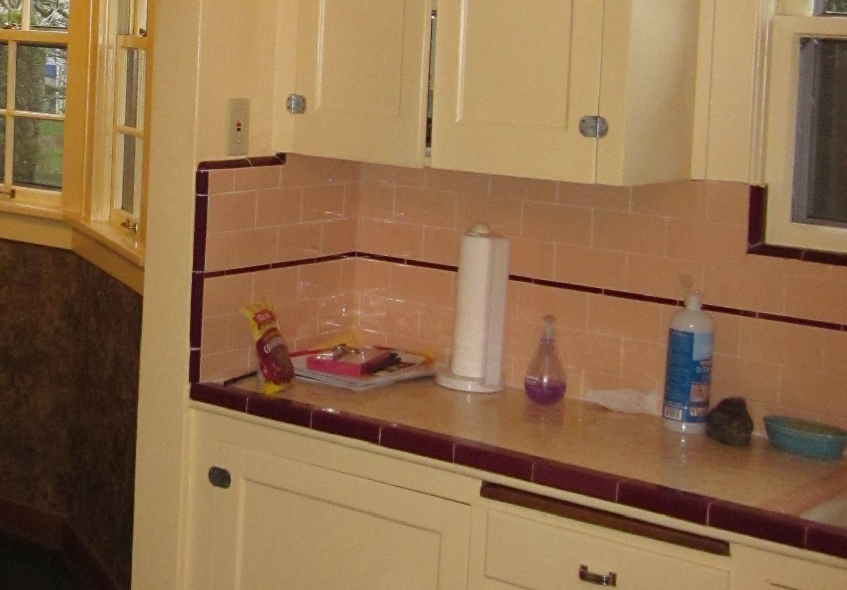 Kitchen countertop with paper towel roll, cleaning supplies, and beige cabinets