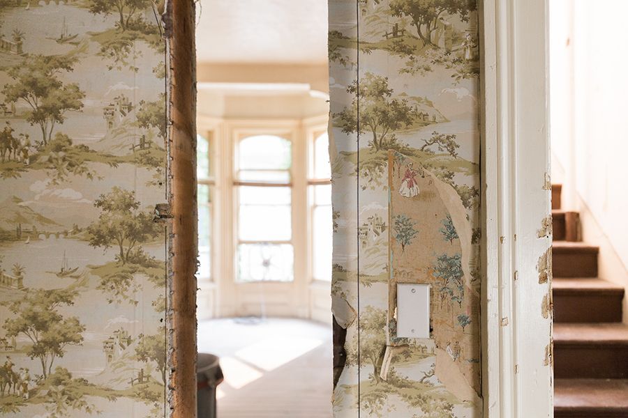 Open doorway to a bright room with floral wallpaper and a staircase on the right.