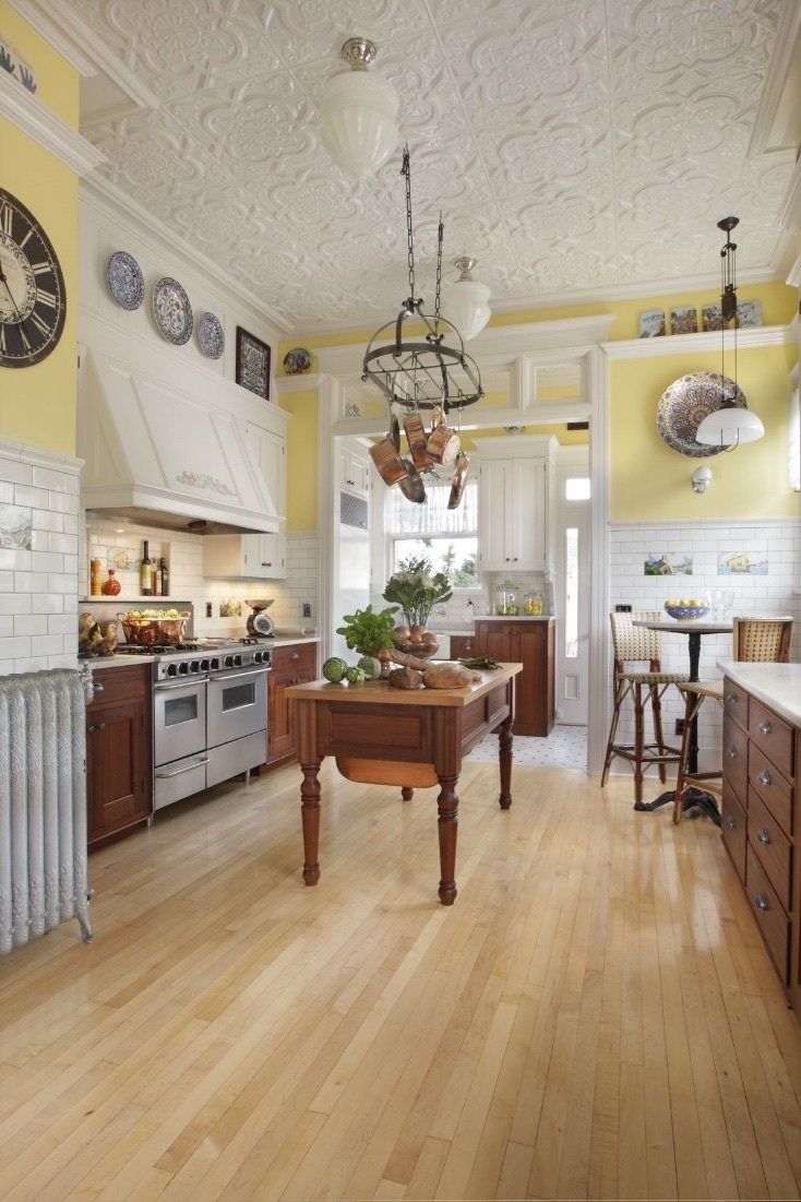 A painted tin ceiling, mahogany cabinets, custard yellow walls and displayed antiques bring charm and depth to this well-loved kitchen. Photo by Greg Kozawa