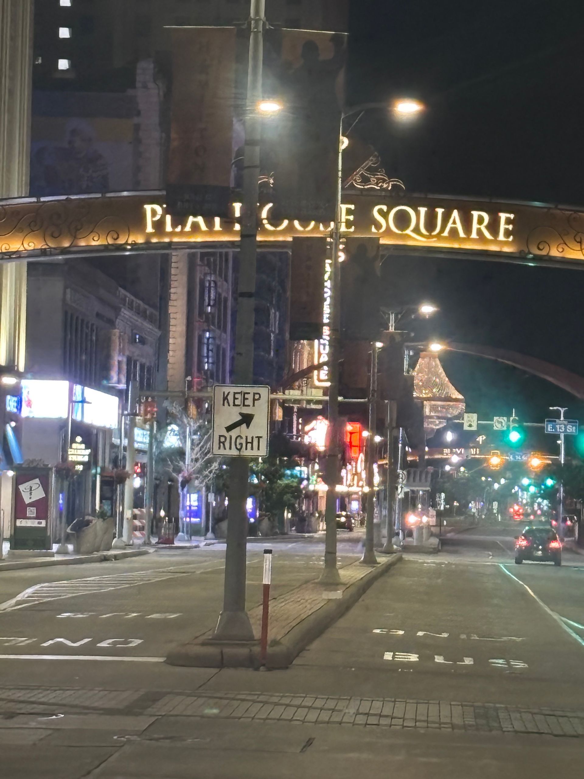 Night street scene under a “PLAYHOUSE SQUARE” sign, with traffic lights, storefronts, and wet pavement.