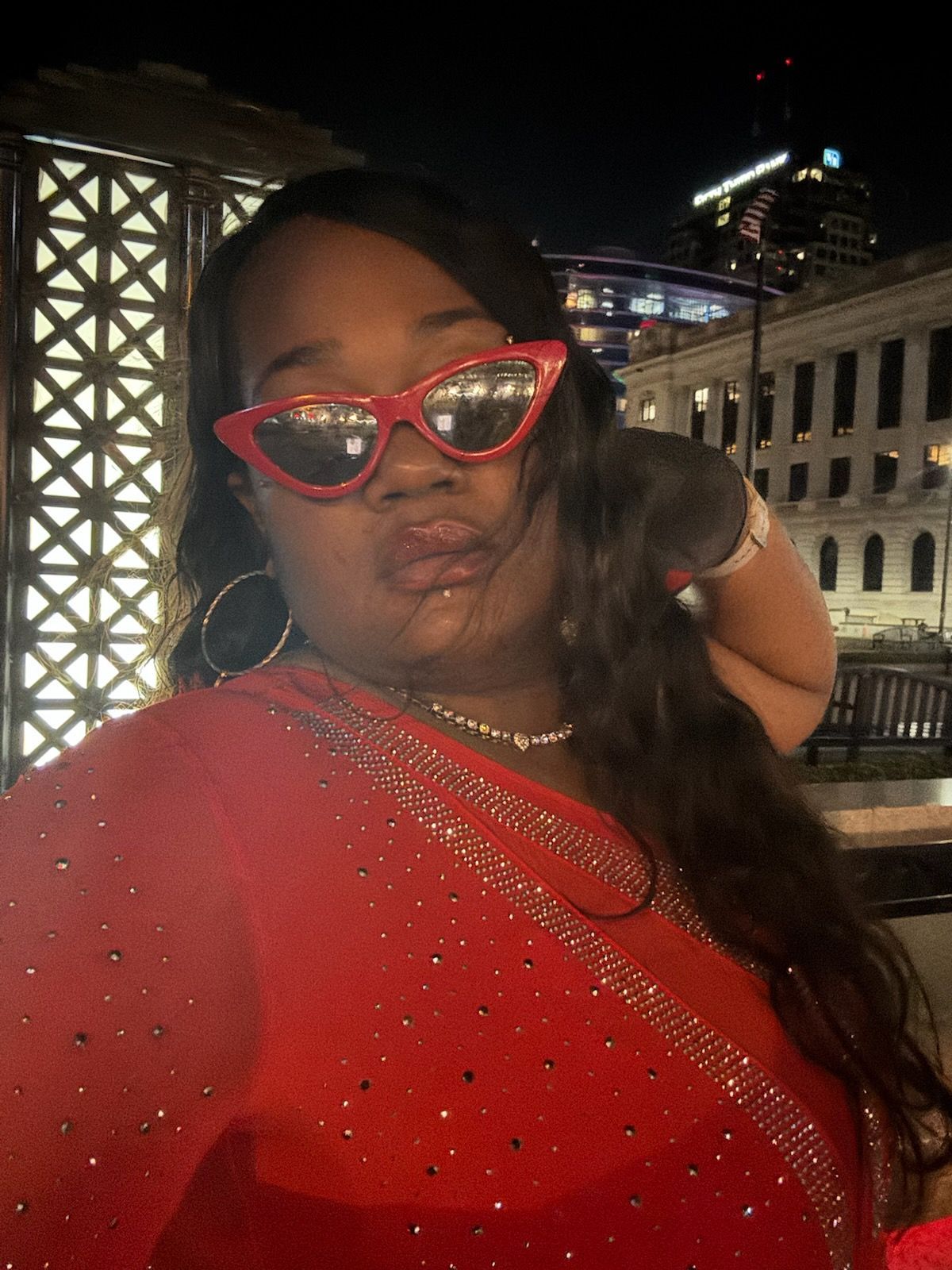 A woman in a red dress and red sunglasses is taking a selfie.