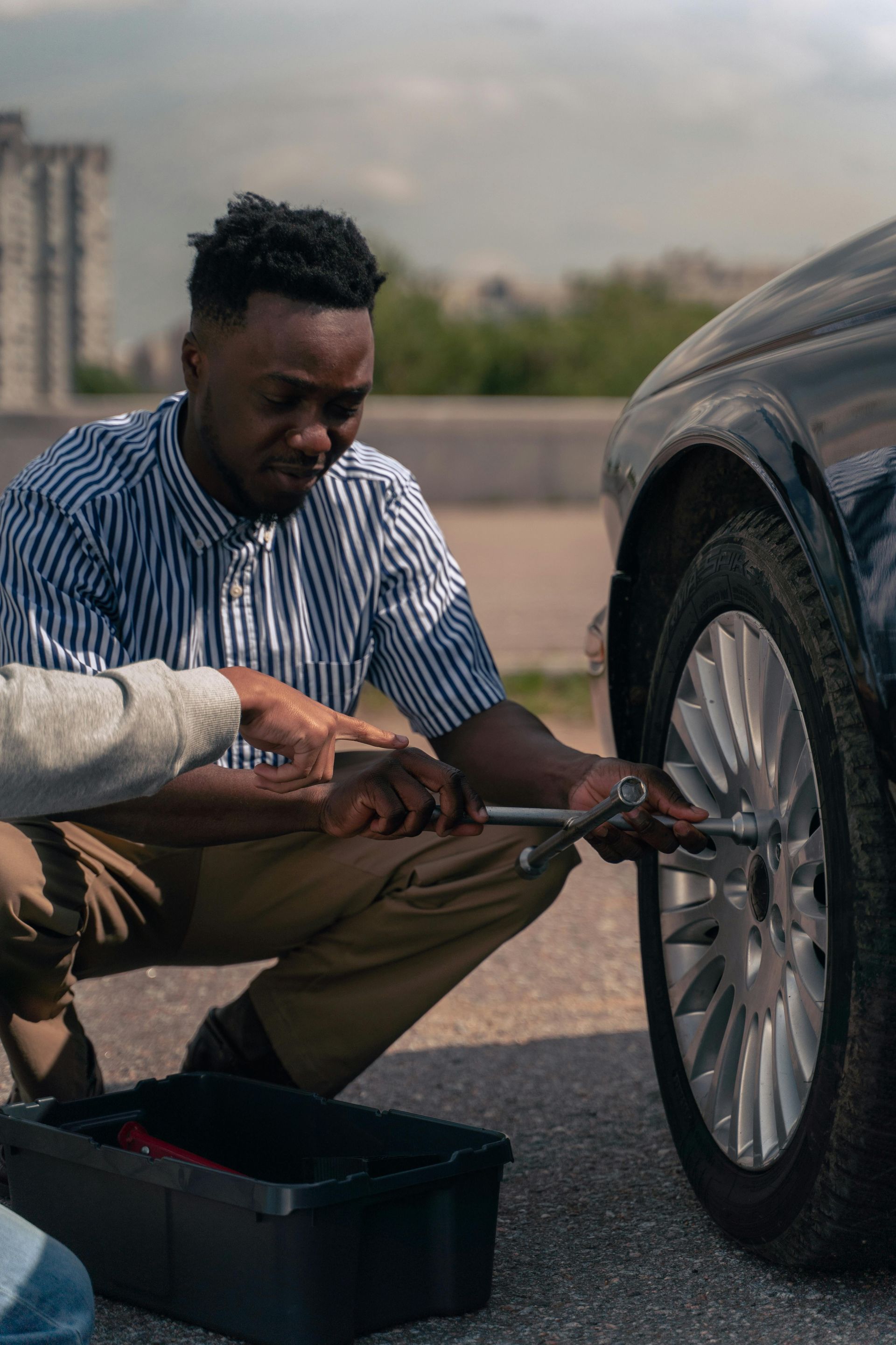 A man is changing a tire on a car with a wrench.